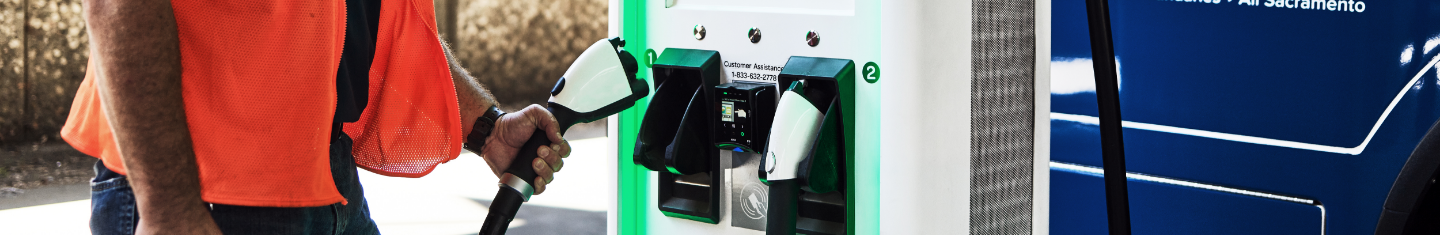 An employee replaces the charger at an Electrify America station