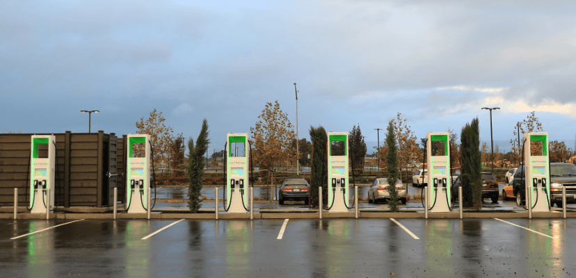 an Electrify America charging location at dusk displaying six chargers pictured from the corner of the lot