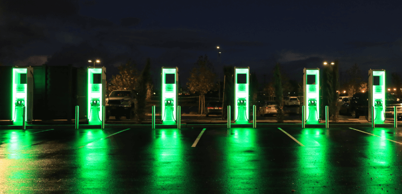 an Electrify America charging location at dusk displaying six chargers pictured from the corner of the lot